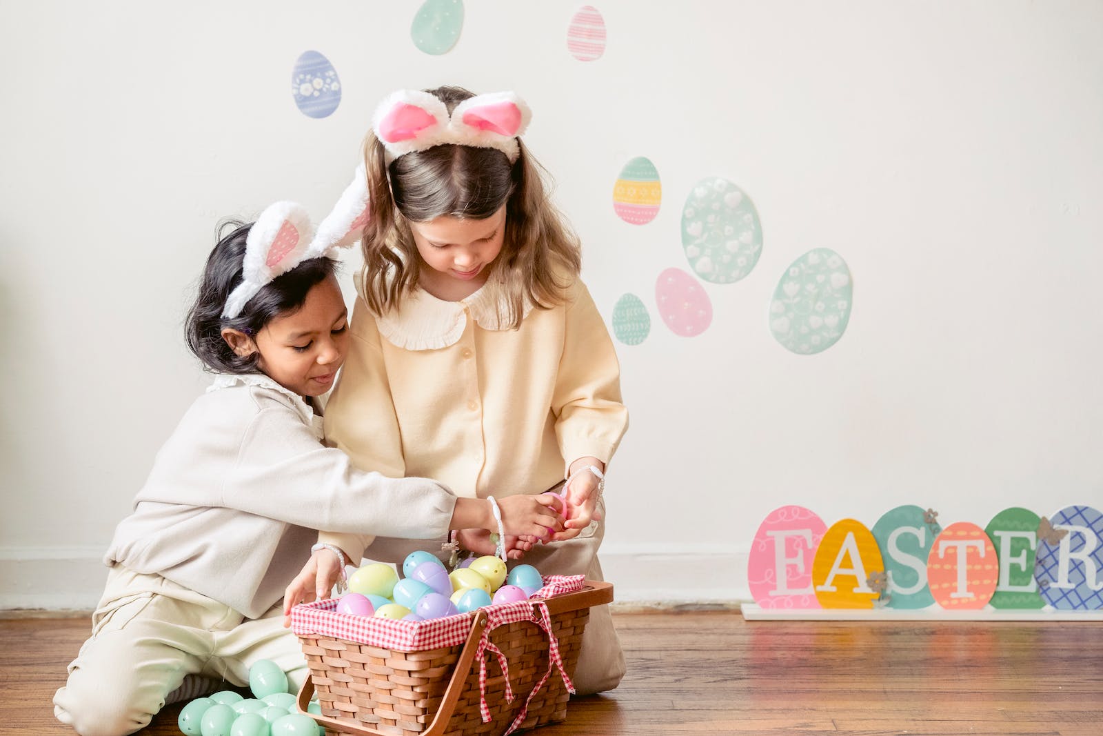 Cute diverse girls playing with colorful Easter eggs